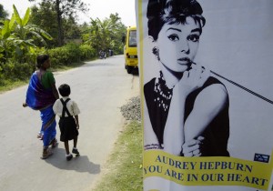 An Indian woman glances at a poster of